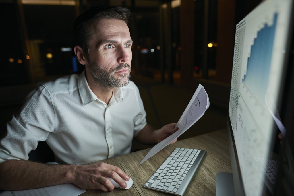 focused man with document using computer
