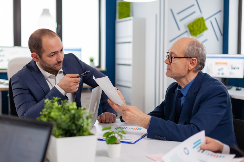 senior entrepreneur discussing with coworker holding documents conference briefing businessman discussing ideas with colleagues about financial strategy new start up company